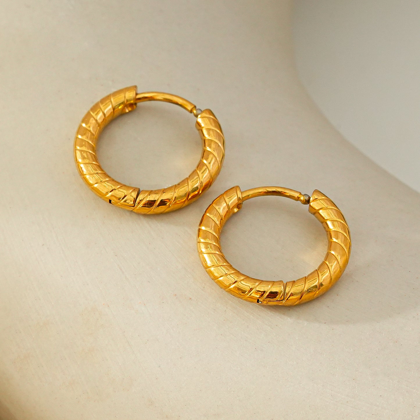 LUPITA: Swirl Design Textured Hoop Earrings in Gold